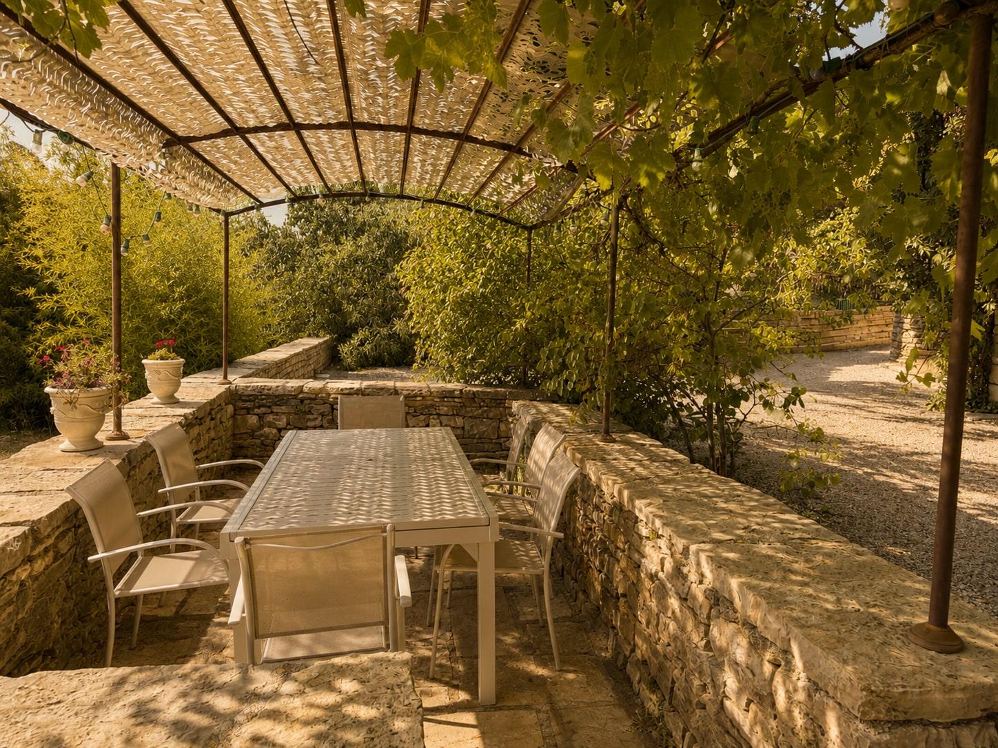 Table sous la pergola, entre les murets de pierre, prête pour le déjeuner.
