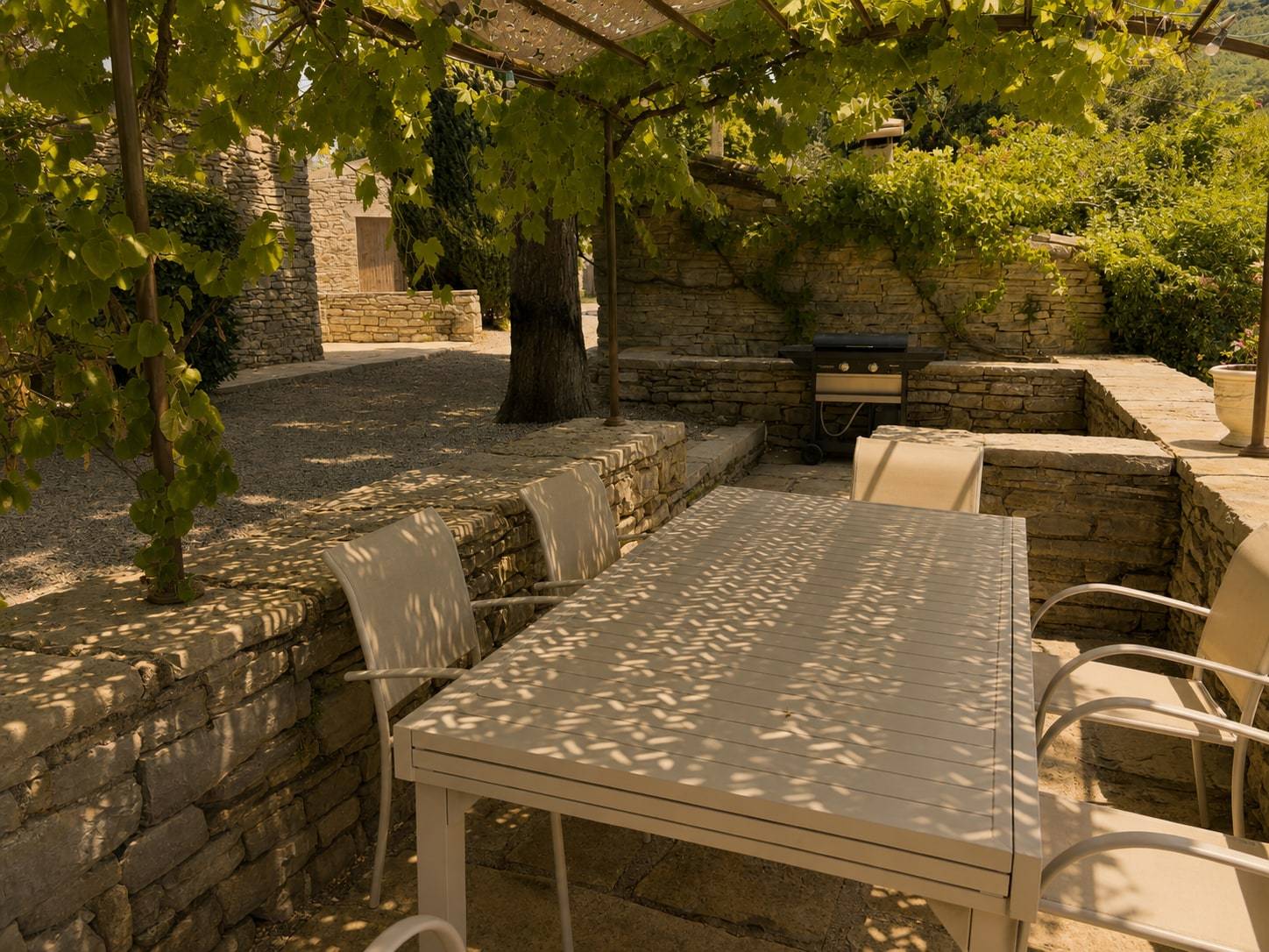 Table sous la treille, entre les murets en pierre sèche, dans la lumière dorée.