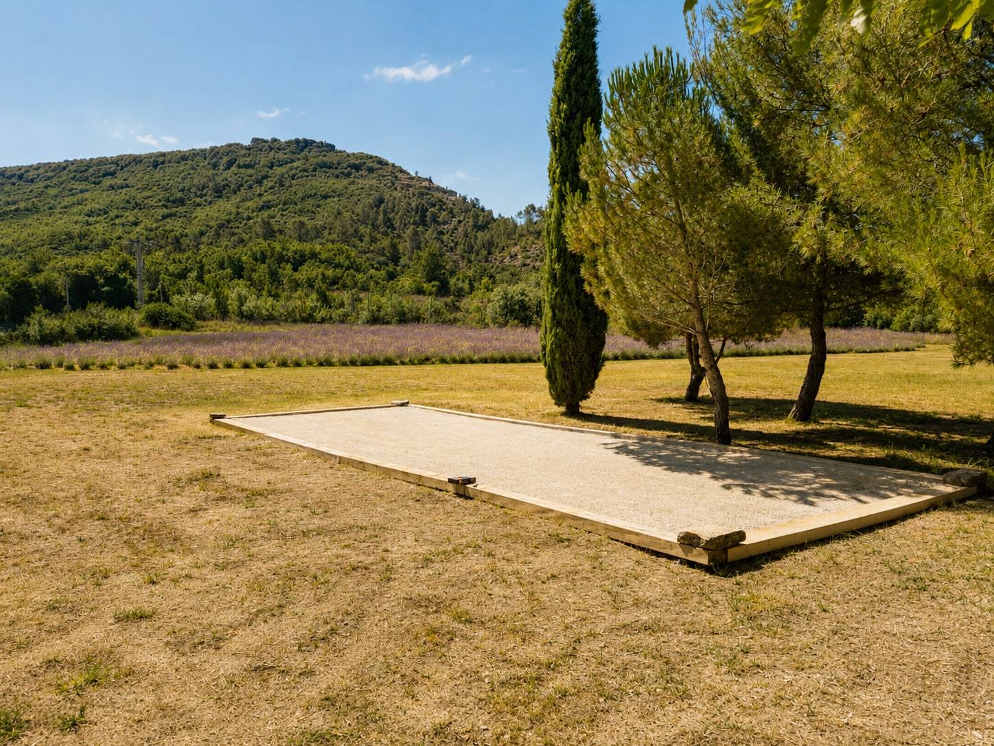 Boulodrome face aux collines, bordé de pins et de cyprès.
