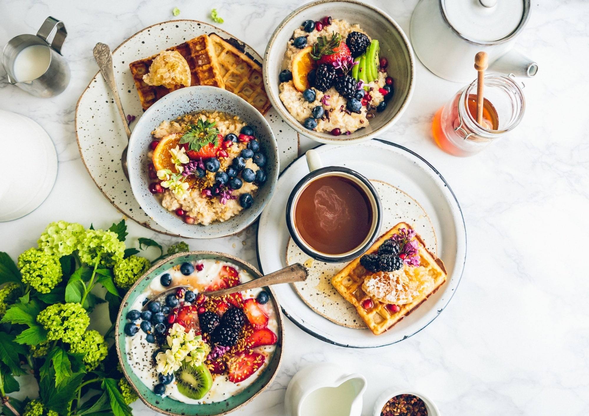 Petit-déjeuner servi sur la table : bols de fruits, gaufres et chocolat chaud.
