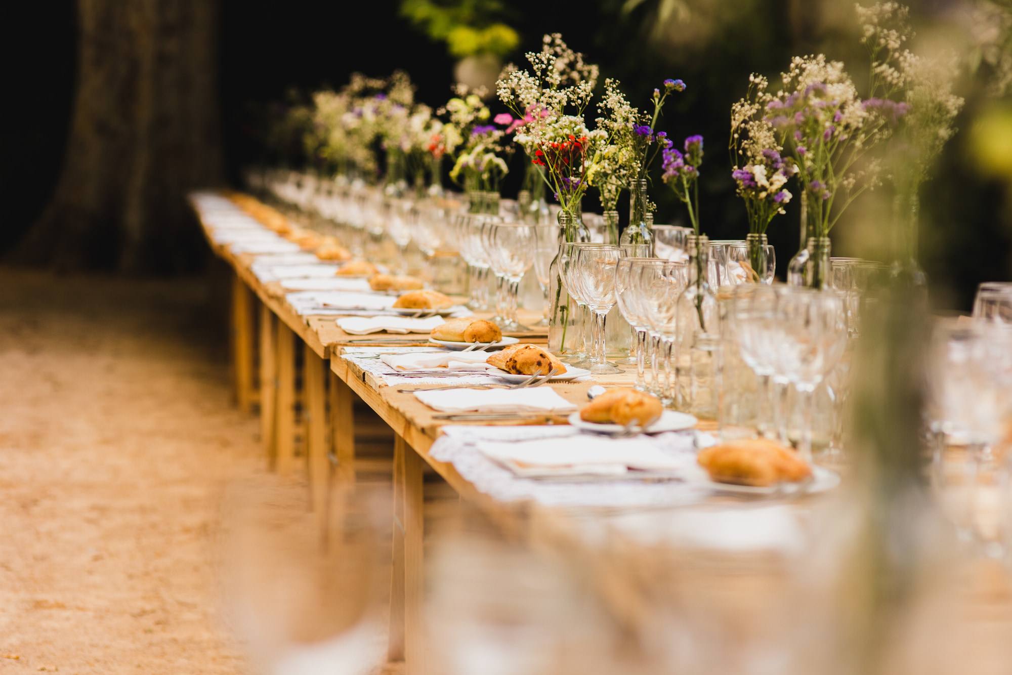Longue table fleurie dressée en extérieur.