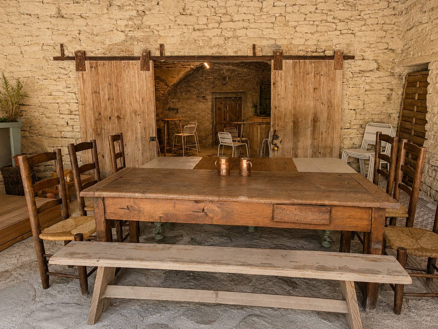 Grande table en bois et bancs sous la voûte en pierre du patio.